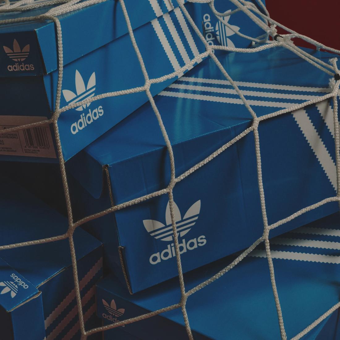 Cajas azules de zapatillas Adidas apiladas dentro de una red blanca