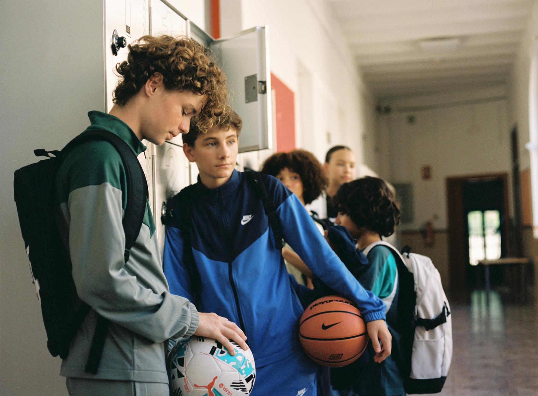 Un grupo de escolares con mochilas y balones en el pasillo del colegio