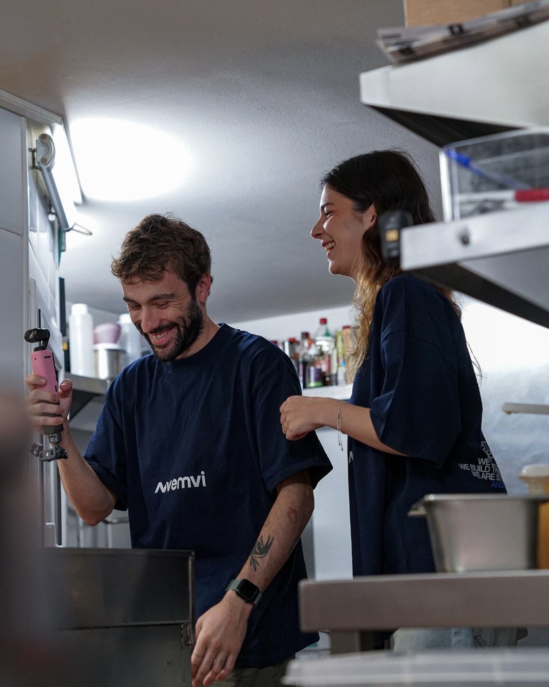 Dos personas del equipo de Emvi ríen mientras graban en una cocina