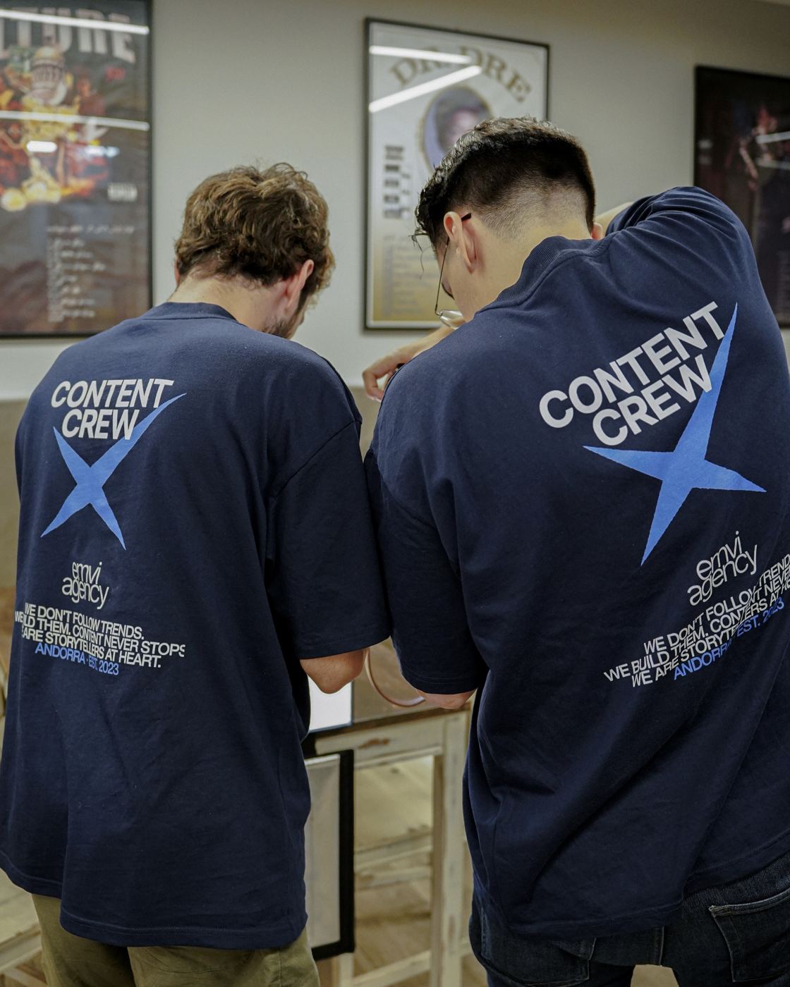 Dos personas del equipo, de espaldas, con camisetas «Content Crew» de Emvi