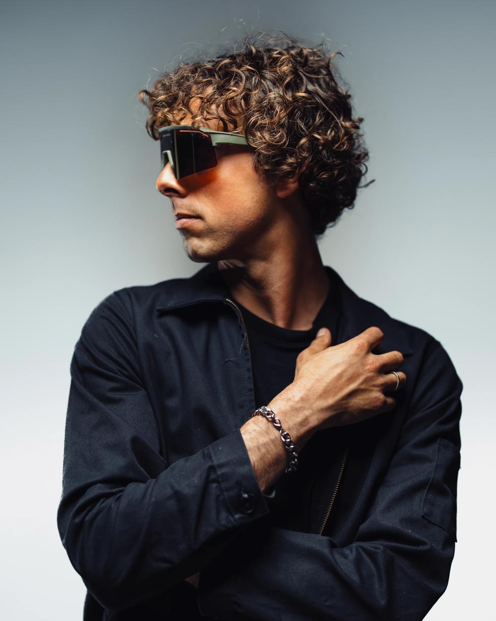 Modelo de pelo rizado con camisa negra y gafas de sol